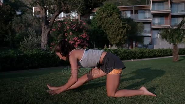 Frau dehnt Beinmuskeln auf dem Boden am Abend im Freien — Stockvideo