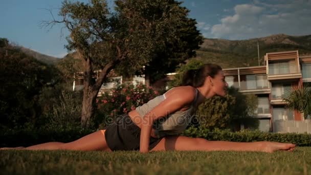 Sport kvinna sitter på marken på vänster split, stretching övningar — Stockvideo