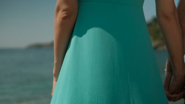 Aan de kust is er een vrouw in een turquoise lange jurk. — Stockvideo