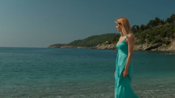 Aantrekkelijke vrouw wandelingen langs de kust op een zonnige dag in de buitenlucht. — Stockvideo
