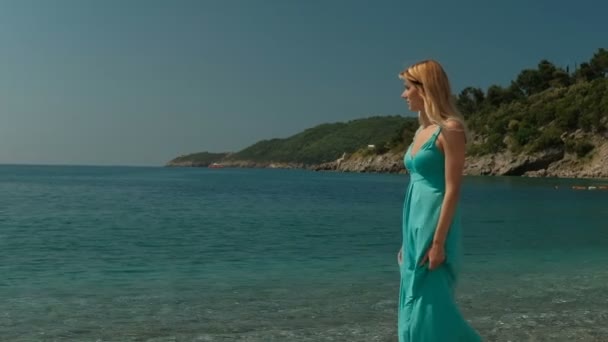 Attractive woman strolls along coast on sunny day outdoors. — Stock Video