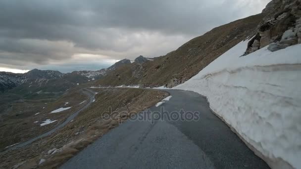 Guidando una macchina lungo la strada di montagna in autunno sera nuvolosa all'aperto sulla valle sinistra, una fitta neve pressata sulla destra . — Video Stock