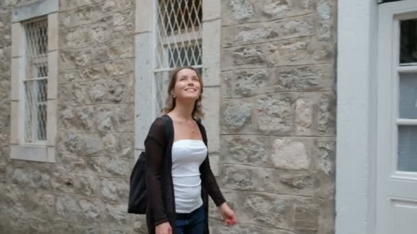 Mulher felizmente caminha pelas antigas ruas de pedra durante a viagem . — Vídeo de Stock