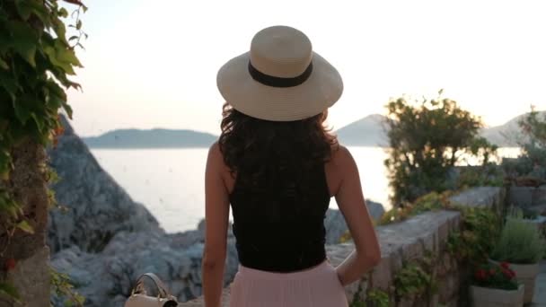 Brunette with luxurious curls and hat stand with back and look at sea. — Stock Video