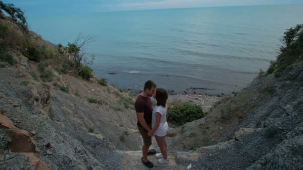 Attractive couple kissing standing on rock by sea shore on summer day outdoors. — Stock Video