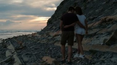 Akşamları kayalık bir sahilde yürüyüş aşık genç Çift.