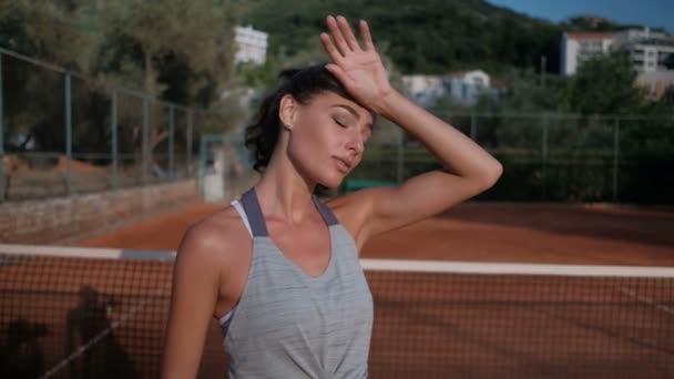 Hermosa morena arregla el pelo y estira los brazos mientras está de pie en el estadio en verano . — Vídeo de stock