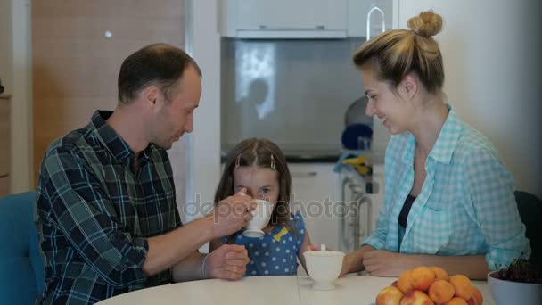 A family of three people drinks a drink and has a cheerful mood. — Stock Video