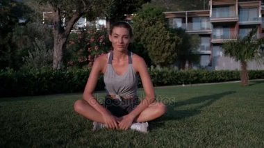 Genç esmer yeşil çimenlerin üzerine yaz sabahı açık oturur..