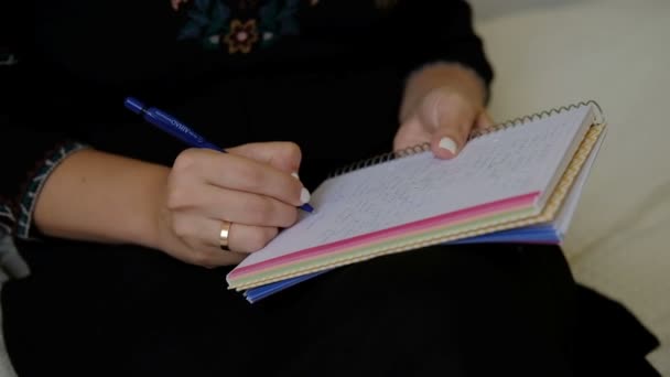 Las manos femeninas escriben una carta sosteniendo un cuaderno en su regazo . — Vídeo de stock