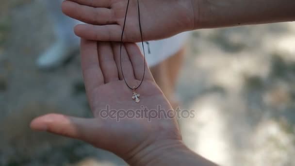 Nelle mani umane giace una piccola croce d'oro ortodossa su una corda . — Video Stock
