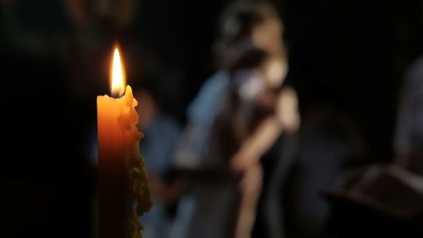Jeune femme tient un petit enfant debout près d'une bougie allumée dans la nuit noire .