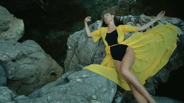 Приваблива жінка лежить на скелі на березі моря в літній день . — стокове відео