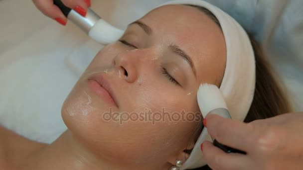 Wykwalifikowanej kosmetyczki sprawia, że twarz masaż z frędzlami leżącej kobiety w salonie spa. — Wideo stockowe