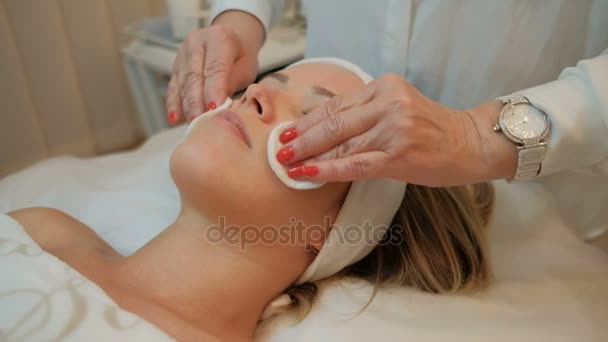 Cosmetologo esperto cotone idrofilo rilassa la pelle del viso delle donne . — Video Stock
