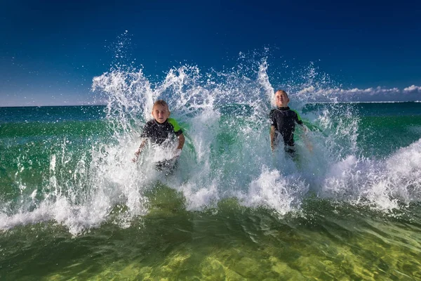 Pojkar bad och lek med havets vågor — Stockfoto