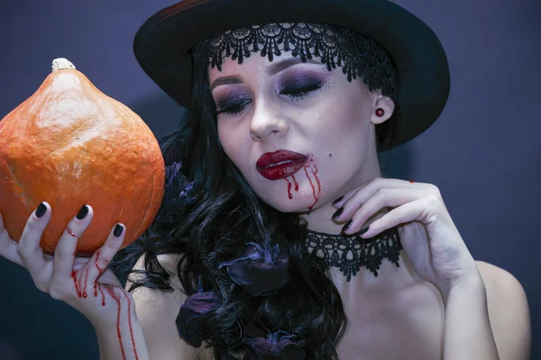 Portrait of a gorgeous brunette with a hat and pumpkin over blac — Stock Photo, Image