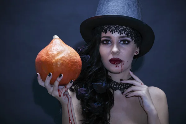 Portrait of a gorgeous brunette with a hat and pumpkin over blac — Stock Photo, Image