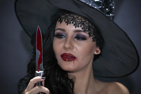 Closeup portrait of woman with bloody knife in her hand in the d — Stock Photo, Image