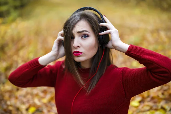Mladá kavkazské bruneta žena se sluchátky venku na podzim — Stock fotografie