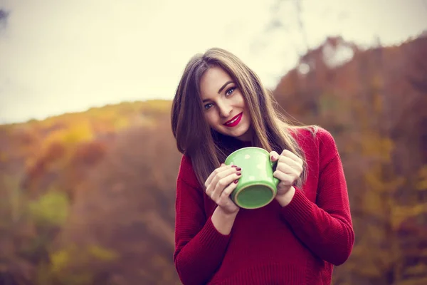 Concepto de otoño - mujer de otoño beber café en el banco del parque bajo — Foto de Stock