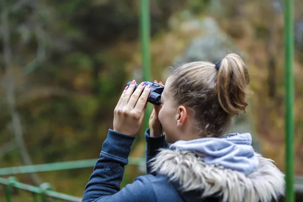 Fiatal szőke nő turisztikai egy sziklán, nézegette a távcső — Stock Fotó