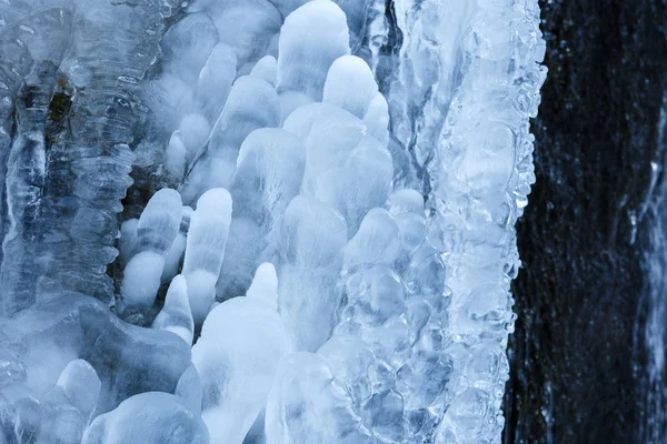 Ghiaccioli ghiacciati sulla parete rocciosa della montagna, primo piano con selec — Foto Stock