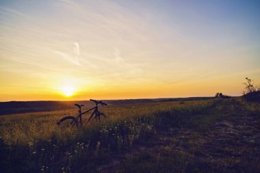 Çim bir bisiklet ile günbatımında manzara