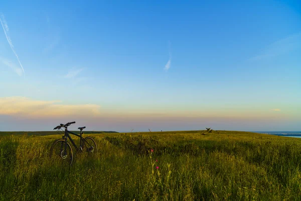 Paisaje con una bicicleta en la hierba al atardecer — Foto de Stock