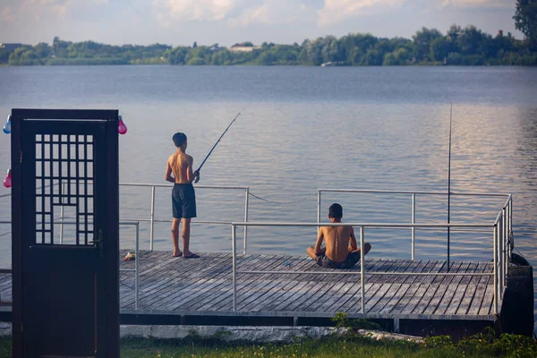 Giovane ragazzo pesca su un pontone sul lago — Foto Stock