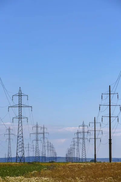 Postes de alta tensión en un campo — Foto de Stock