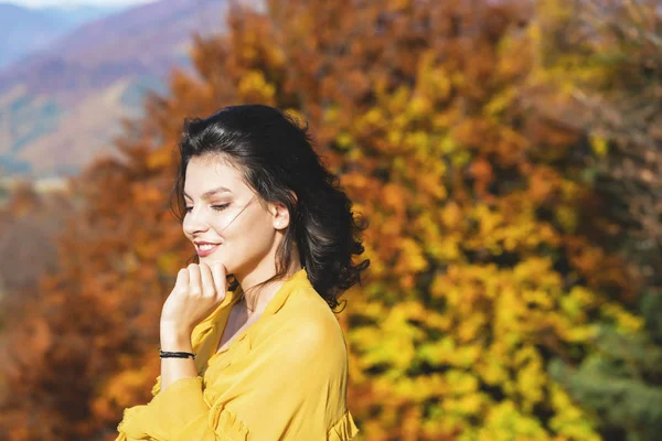 Beautiful young brunette enjoys a sunny day of autumn in nature — Stock Photo, Image