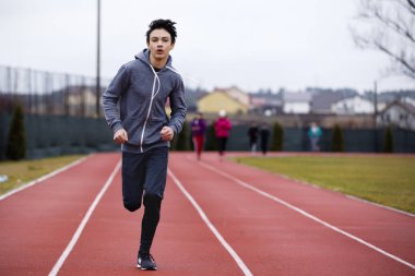 Stadyumda yarış pisti üzerinde çalışan atlet Asya genç adam. Sağlıklı