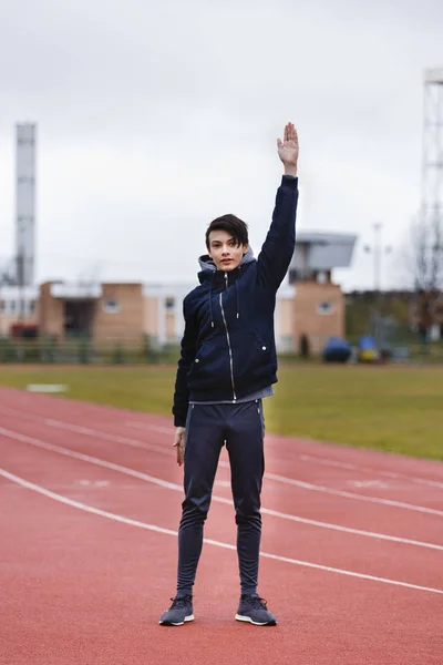 Joven deportista hace ejercicios en una pista de carreras —  Fotos de Stock