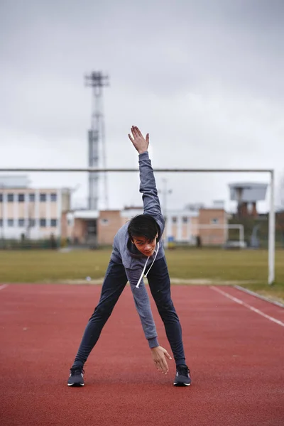 Joven deportista hace ejercicios en una pista de carreras —  Fotos de Stock