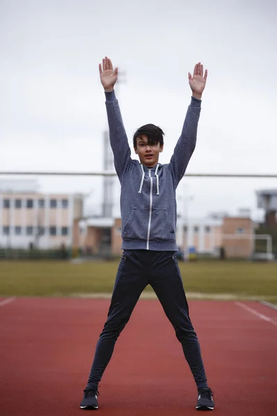 Jovem desportista faz exercícios em uma pista de corrida — Fotografia de Stock