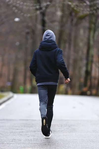 Молодой человек бегает по парку во время дождя — стоковое фото