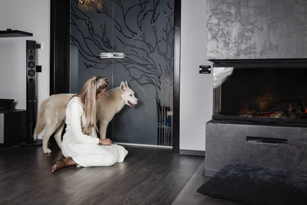Elegant woman near the fireplace with a dog — Stock Photo, Image