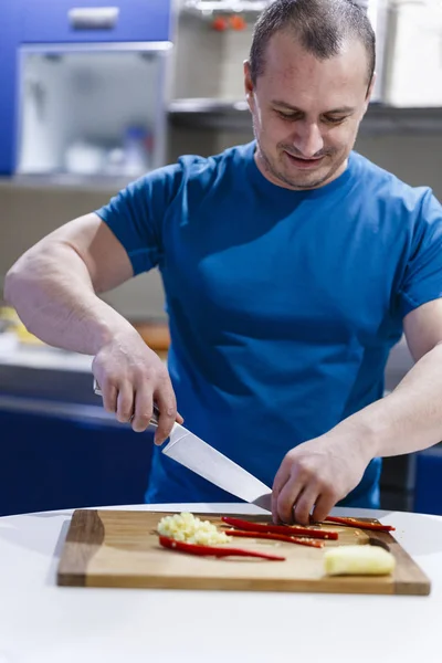 Homme coupe des légumes sur un bois dans la cuisine — Photo