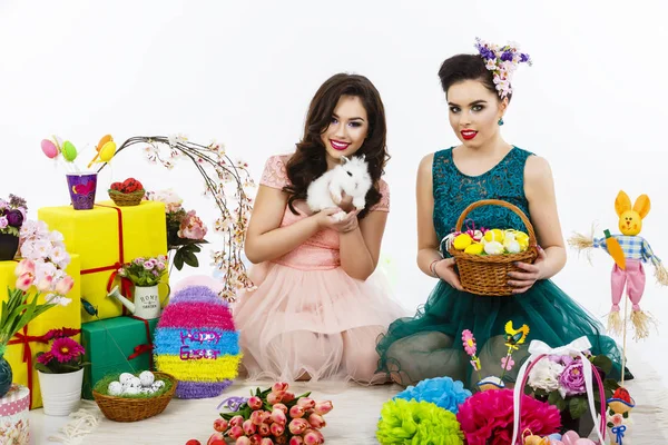 Twee mooie vrouwen spelen in Pasen decoratie met een konijn. — Stockfoto