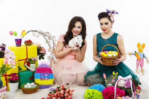 Two beautiful women playing in easter decoration with a rabbit. — Stock Photo, Image