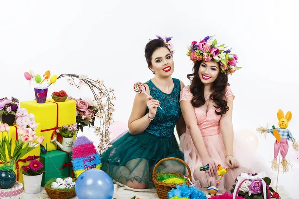 Dvě krásné přítelkyně holky, košík s vejci a dekorativní květina — Stock fotografie