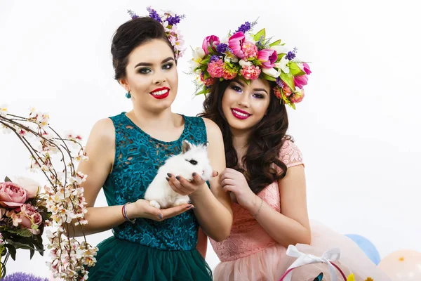 Twee mooie vrouwen spelen in Pasen decoratie met een konijn. — Stockfoto