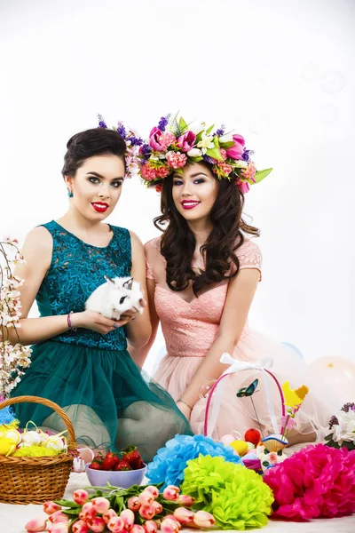 Two beautiful women playing in easter decoration with a rabbit. — Stock Photo, Image