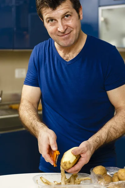 Człowiek, obieranie ziemniaków na blacie w kuchni — Zdjęcie stockowe