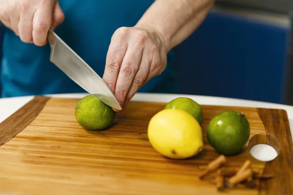 Человек режет лаймы и лимоны на деревянной доске — стоковое фото