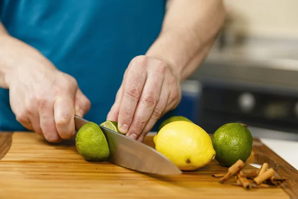 Man slicing limes and lemons on a wooden board