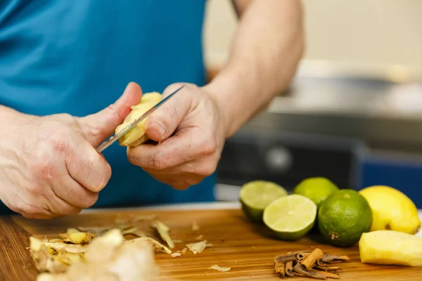 Hombre cortando jengibre en una tabla de madera, primer plano — Foto de Stock