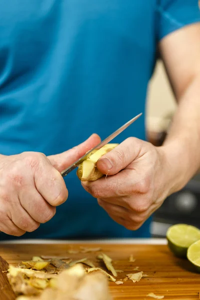 Uomo che taglia lo zenzero su una tavola di legno, primo piano colpo — Foto Stock