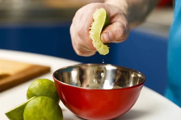 Uomo spremere mezza calce in una ciotola, messa a fuoco selettiva — Foto Stock